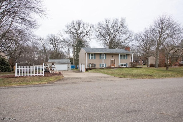 split foyer home with an outbuilding, a detached garage, fence, a chimney, and a front yard