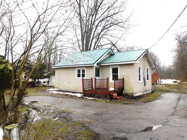 view of front of property featuring a deck, metal roof, and aphalt driveway