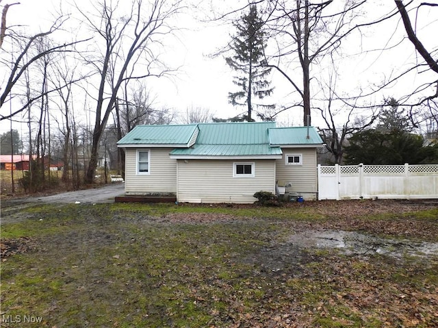 rear view of house featuring metal roof and fence