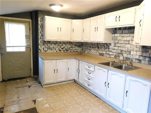 kitchen with light floors, white cabinets, a sink, and light countertops