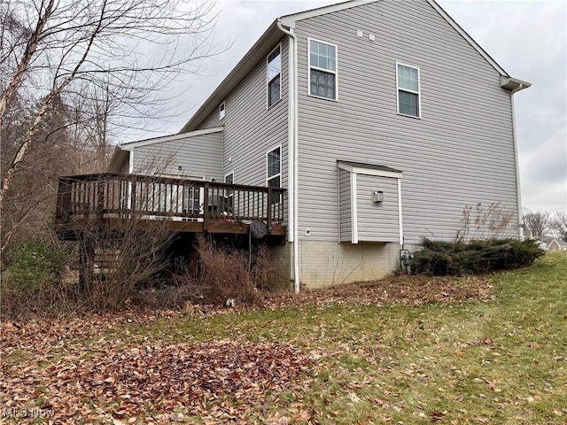 view of side of home with a deck and a lawn