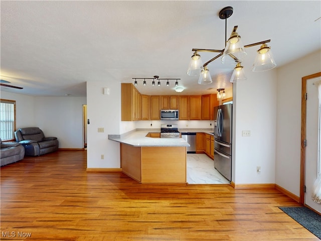 kitchen featuring open floor plan, stainless steel appliances, light wood-type flooring, and a peninsula