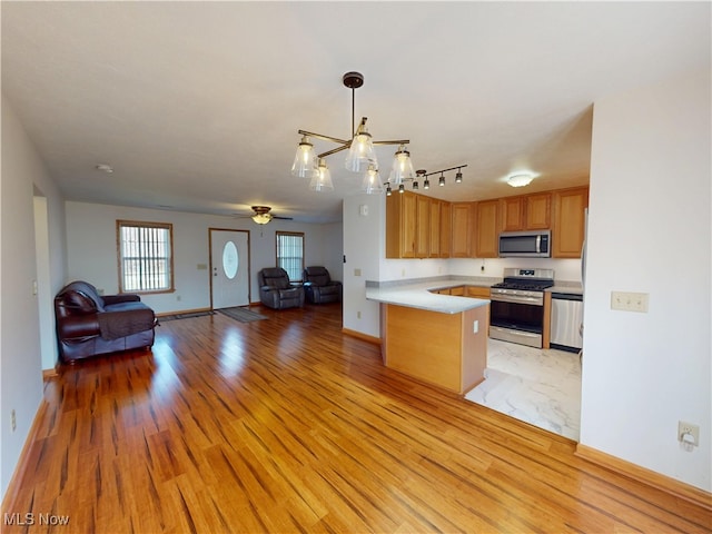 kitchen featuring stainless steel appliances, open floor plan, light countertops, and a peninsula