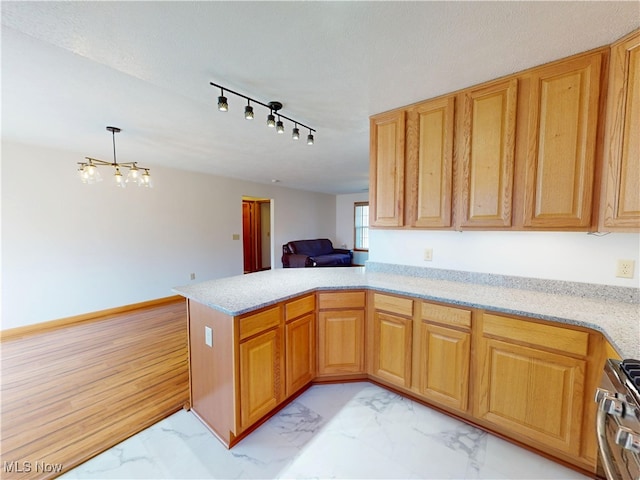 kitchen featuring a peninsula, stainless steel range with gas stovetop, marble finish floor, decorative light fixtures, and an inviting chandelier