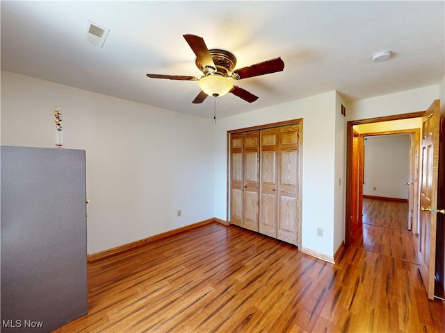 unfurnished bedroom featuring baseboards, ceiling fan, a closet, and light wood-style floors