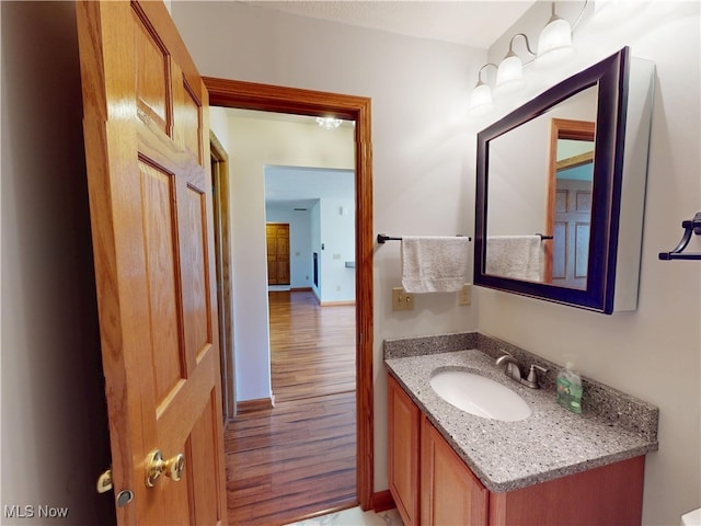 bathroom with wood finished floors, vanity, and baseboards