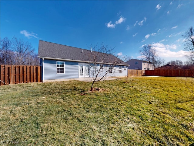 rear view of property featuring a fenced backyard, roof with shingles, a lawn, and french doors