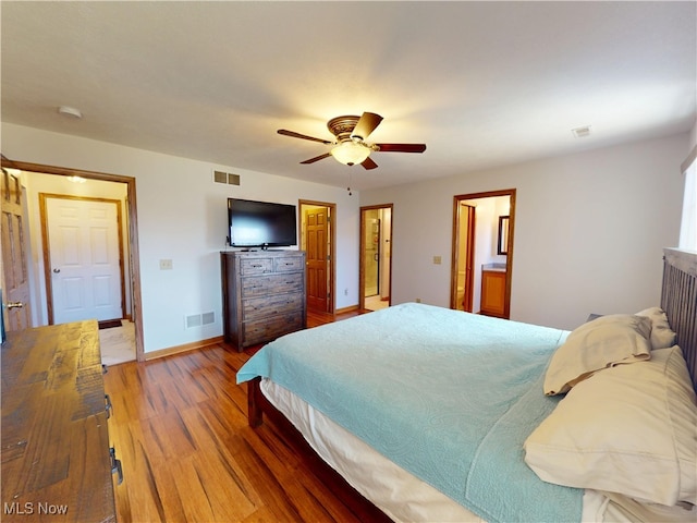 bedroom with a ceiling fan, wood finished floors, visible vents, and baseboards