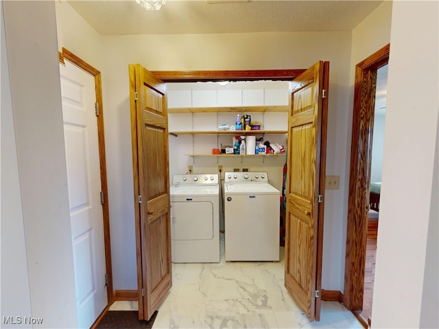 washroom featuring marble finish floor, washing machine and dryer, laundry area, and a textured ceiling