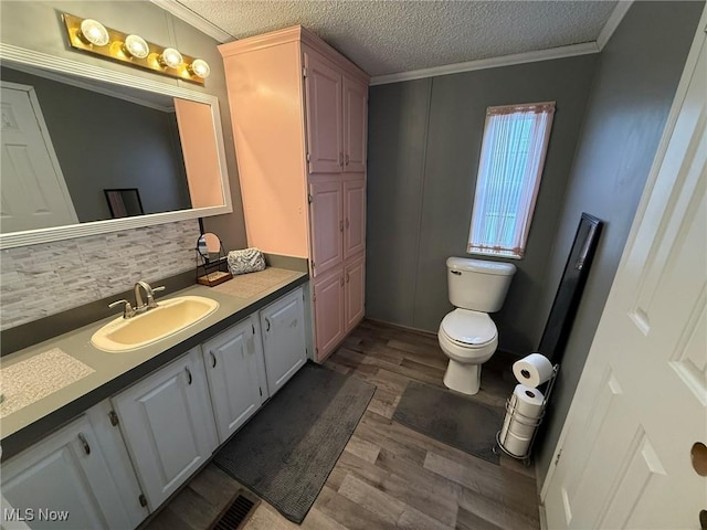 bathroom featuring toilet, a textured ceiling, wood finished floors, and vanity