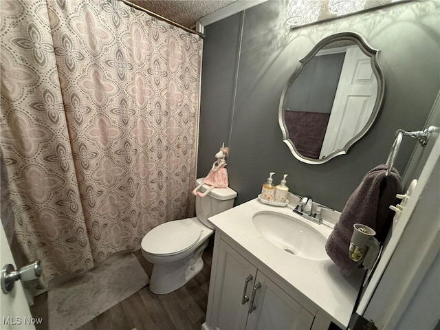 full bathroom with a textured ceiling, curtained shower, toilet, wood finished floors, and vanity