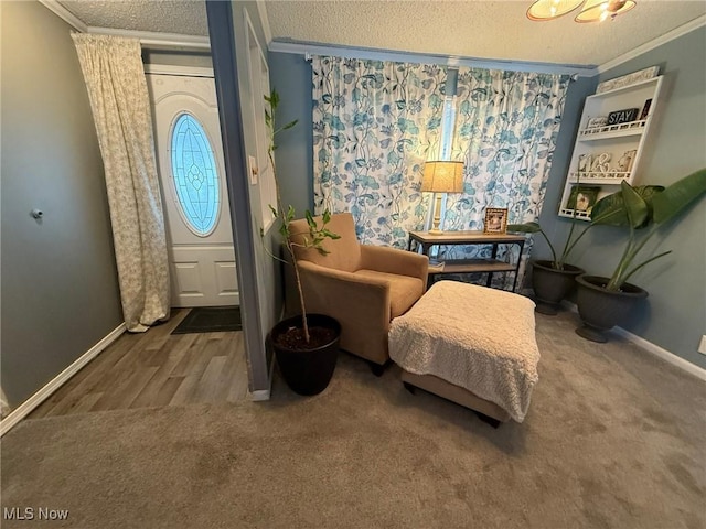 foyer with carpet flooring, crown molding, a textured ceiling, and baseboards