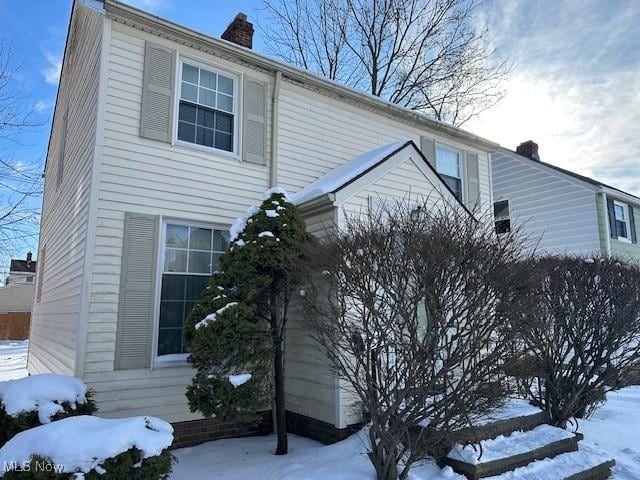 view of snow covered exterior with a chimney