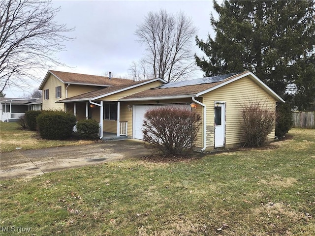 view of front of home with solar panels, concrete driveway, an attached garage, fence, and a front yard