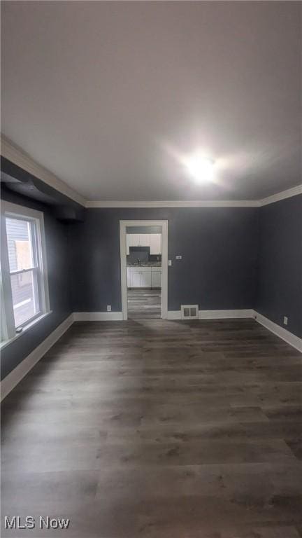 empty room featuring baseboards, visible vents, ornamental molding, and dark wood-type flooring