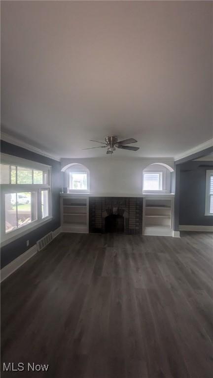 unfurnished living room featuring baseboards, a fireplace, visible vents, and wood finished floors