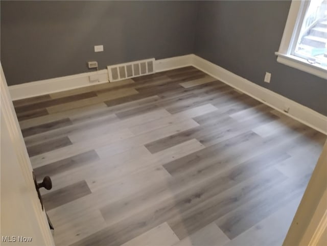 spare room featuring visible vents, baseboards, and wood finished floors