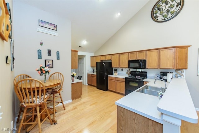 kitchen featuring light wood-type flooring, black appliances, light countertops, and a sink