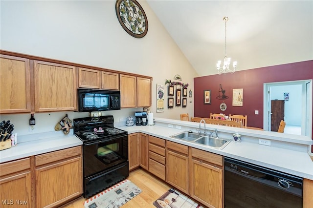 kitchen featuring a peninsula, a sink, light countertops, light wood-type flooring, and black appliances