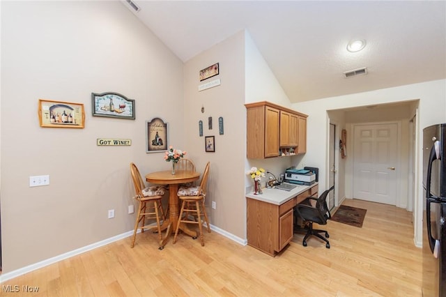 office area featuring lofted ceiling, light wood finished floors, baseboards, and visible vents