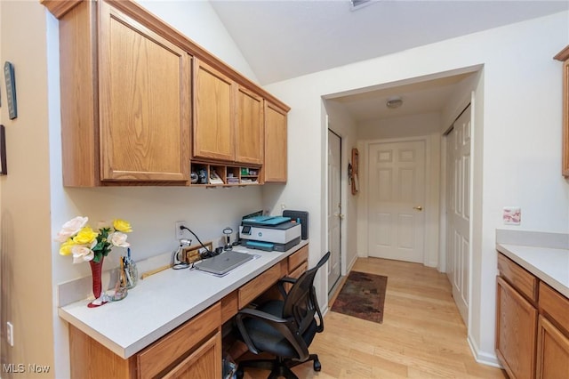 office with light wood-type flooring, built in study area, vaulted ceiling, and baseboards