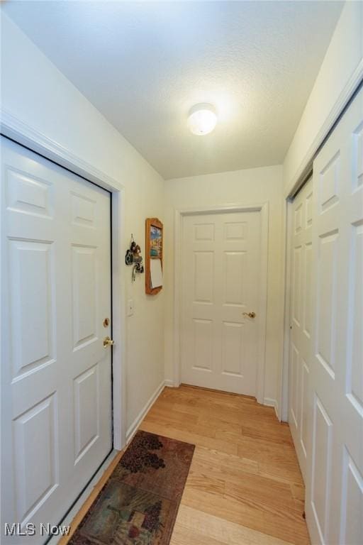 doorway to outside with light wood-type flooring and baseboards