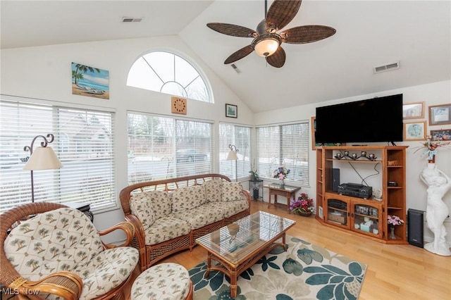 living area with high vaulted ceiling, visible vents, ceiling fan, and wood finished floors