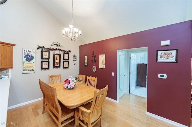 dining space featuring light wood-type flooring, lofted ceiling, a chandelier, and baseboards