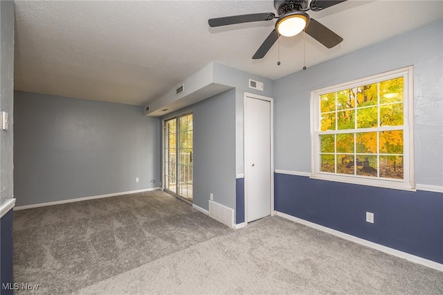 carpeted spare room with visible vents, a textured ceiling, and baseboards