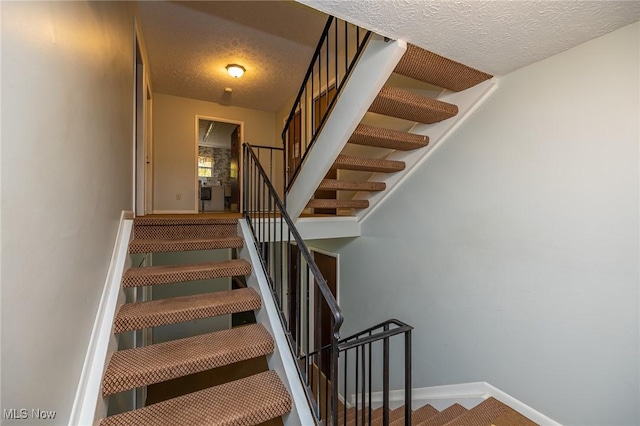 stairs with baseboards and a textured ceiling