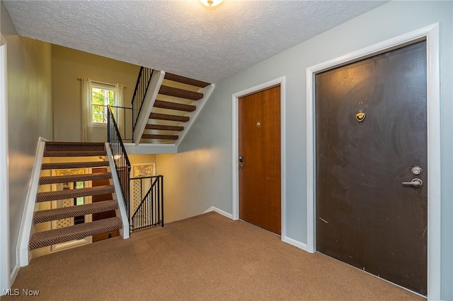 stairway with a textured ceiling and carpet flooring