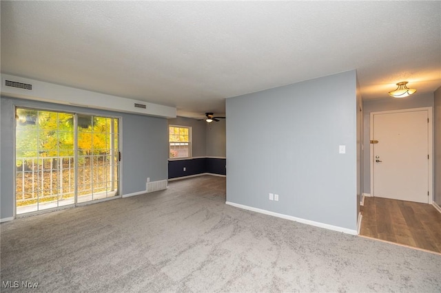 carpeted empty room with visible vents, a textured ceiling, and baseboards