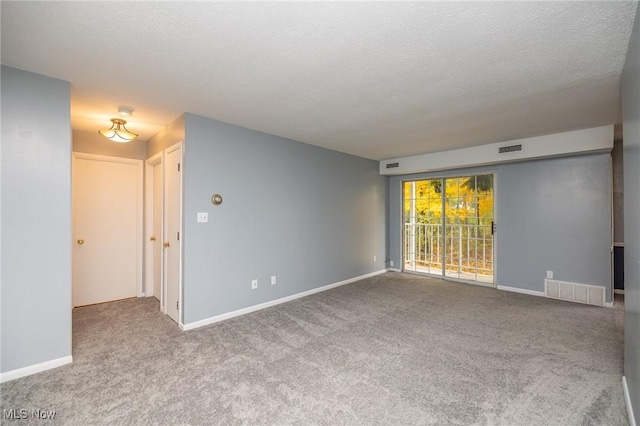 spare room with carpet floors, visible vents, and a textured ceiling