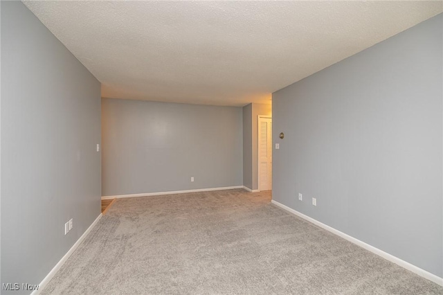 carpeted spare room featuring a textured ceiling and baseboards