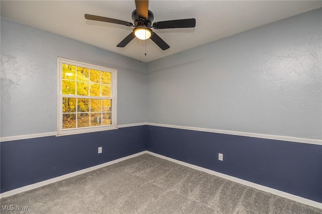 carpeted spare room featuring a ceiling fan and baseboards