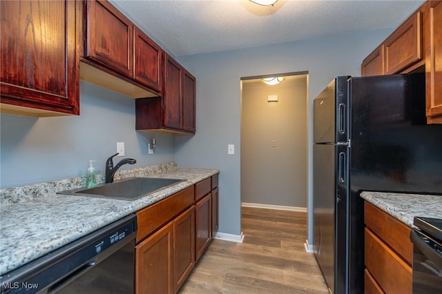 kitchen with a textured ceiling, light wood-style flooring, a sink, baseboards, and black appliances