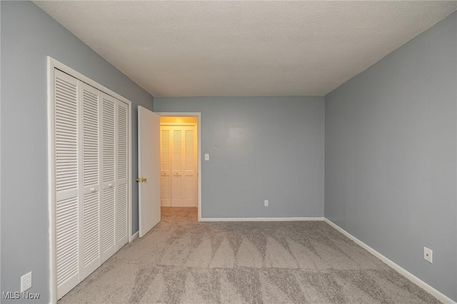 unfurnished bedroom featuring a textured ceiling, a closet, carpet, and baseboards