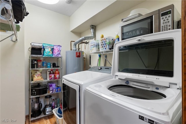 clothes washing area featuring laundry area, water heater, washing machine and clothes dryer, and wood finished floors