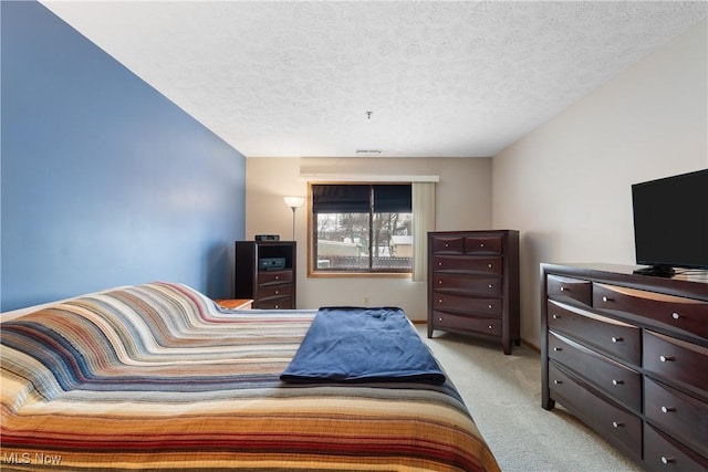 bedroom with a textured ceiling, visible vents, and light colored carpet