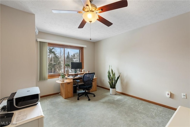 office space with light colored carpet, ceiling fan, a textured ceiling, and baseboards