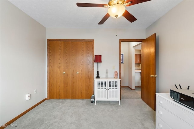 bedroom with light carpet, a closet, a textured ceiling, and baseboards