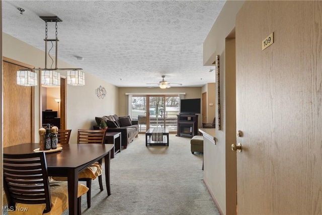 dining space with a textured ceiling, carpet floors, and a ceiling fan