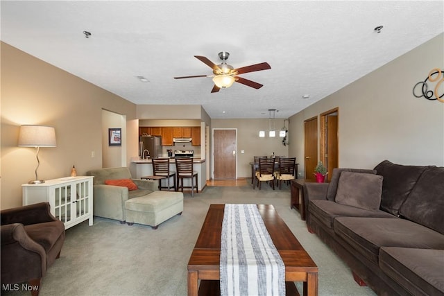 living area featuring ceiling fan, a textured ceiling, and light colored carpet