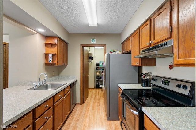 kitchen featuring brown cabinets, stainless steel appliances, light countertops, under cabinet range hood, and a sink