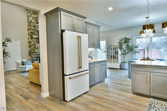 kitchen with an inviting chandelier, gray cabinetry, light wood-style flooring, and freestanding refrigerator