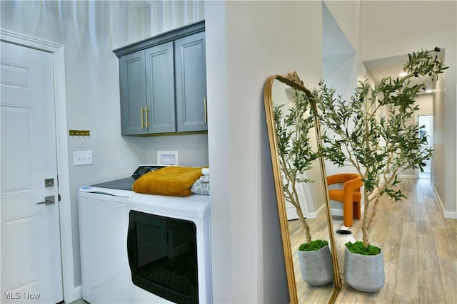 laundry room with washer and dryer, baseboards, cabinet space, and light wood finished floors