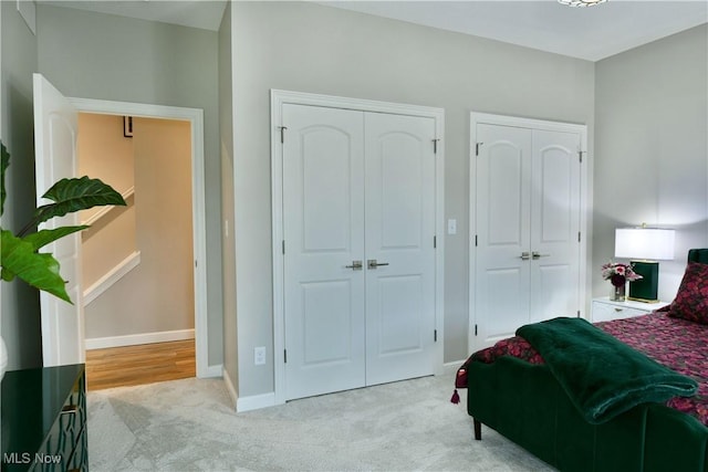 carpeted bedroom with baseboards and two closets