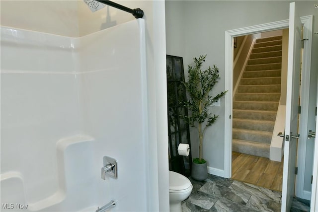 bathroom with bathing tub / shower combination, toilet, and baseboards