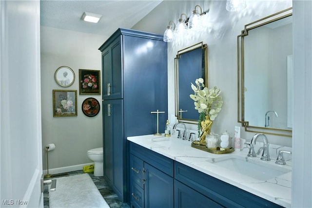 bathroom featuring baseboards, a sink, toilet, and double vanity