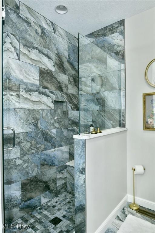 bathroom with visible vents, baseboards, walk in shower, and a textured ceiling